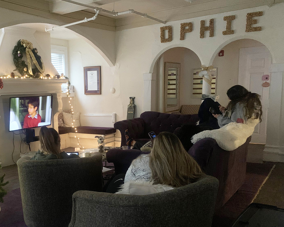 sorority members watching a movie in their house living room